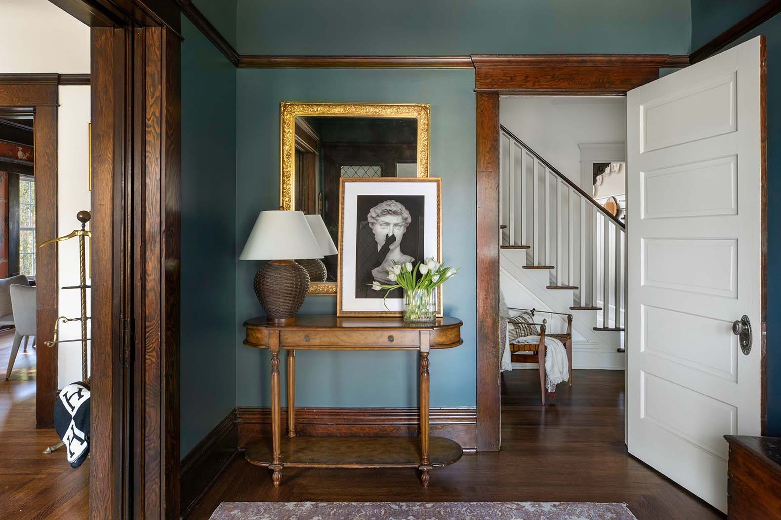 The Craftsman entry hall at The Craft House Inn, with quartersawn oak trim, teal walls, and the staircase beyond an open front door