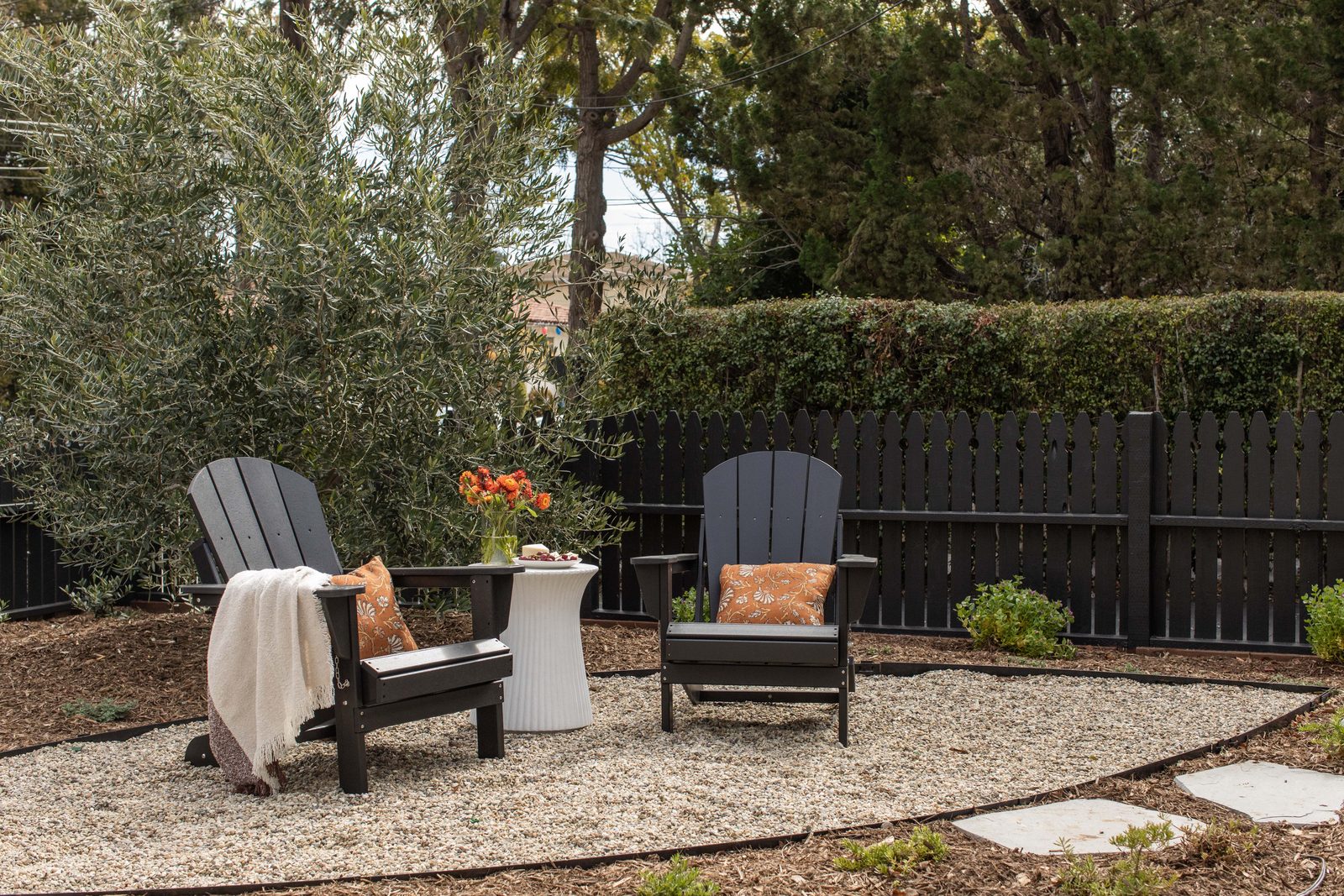 Adirondack chairs beside an olive tree in the garden