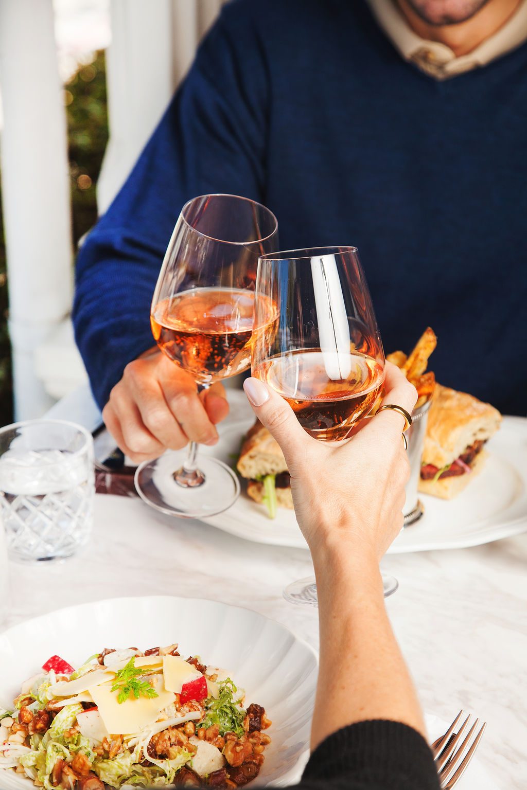 Two guests toasting glasses of rosé over lunch, part of the Savor & Stay package
